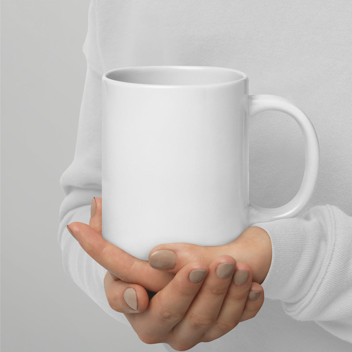 Plain white ceramic mug held in hands, smooth blank front